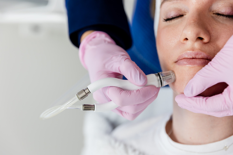 A provider conducts a DiamondGlow facial, not a HydraFacial in Philadelphia, by gliding the treatment device across a patient's face.