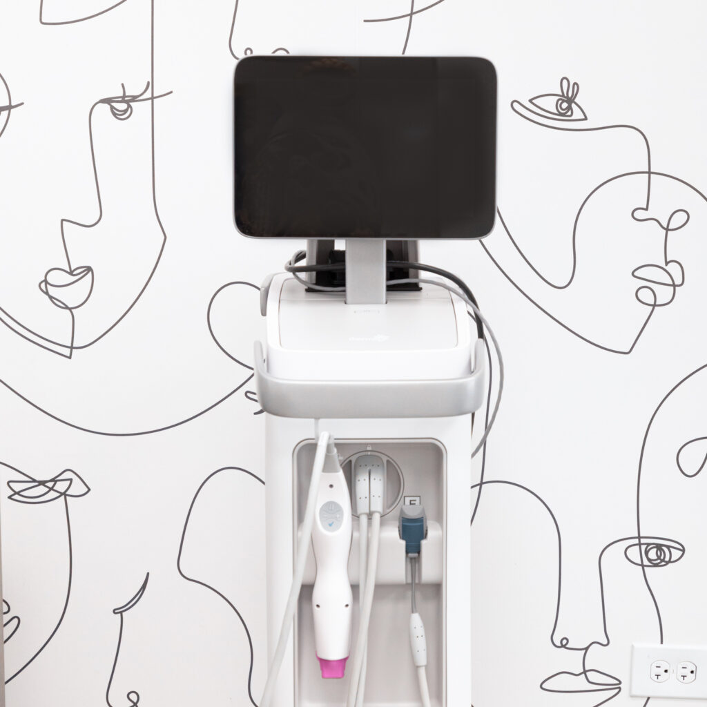 L'appareil Thermage FLX se trouve devant le papier peint abstrait du bureau d'About Face Aesthetics. Cet appareil peut être utilisé pour le Thermage des bajoues à Philadelphie, raffermissant la peau et rétablissant la définition de la mâchoire.